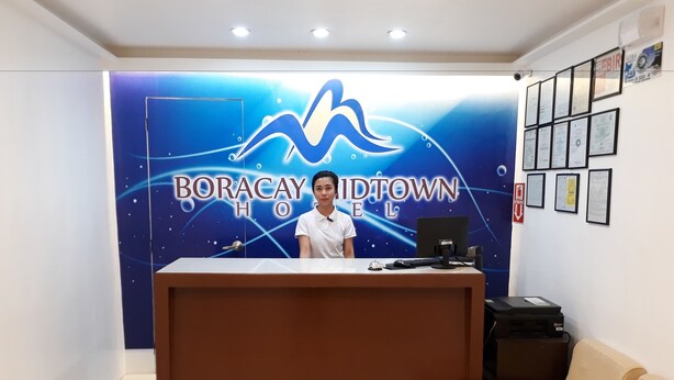 A reception desk with a blue backdrop featuring the text "BORACAY BIDTOWN HOTEL". - Boracay Midtown Hotel (Boracay Island)