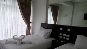 A hotel room with two beds, a large mirror, and a nightstand with a phone and a book. - Boracay Midtown Hotel (Boracay Island)