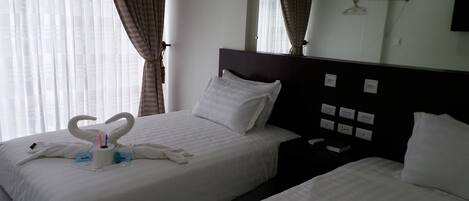 A hotel room with two beds, a large mirror, and a nightstand with a phone and a book.