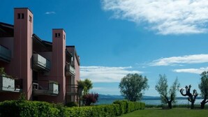 A multi-story hotel with balconies, a clear view of the lake, and a well-maintained garden. - Virgilio Residence (Sirmione)