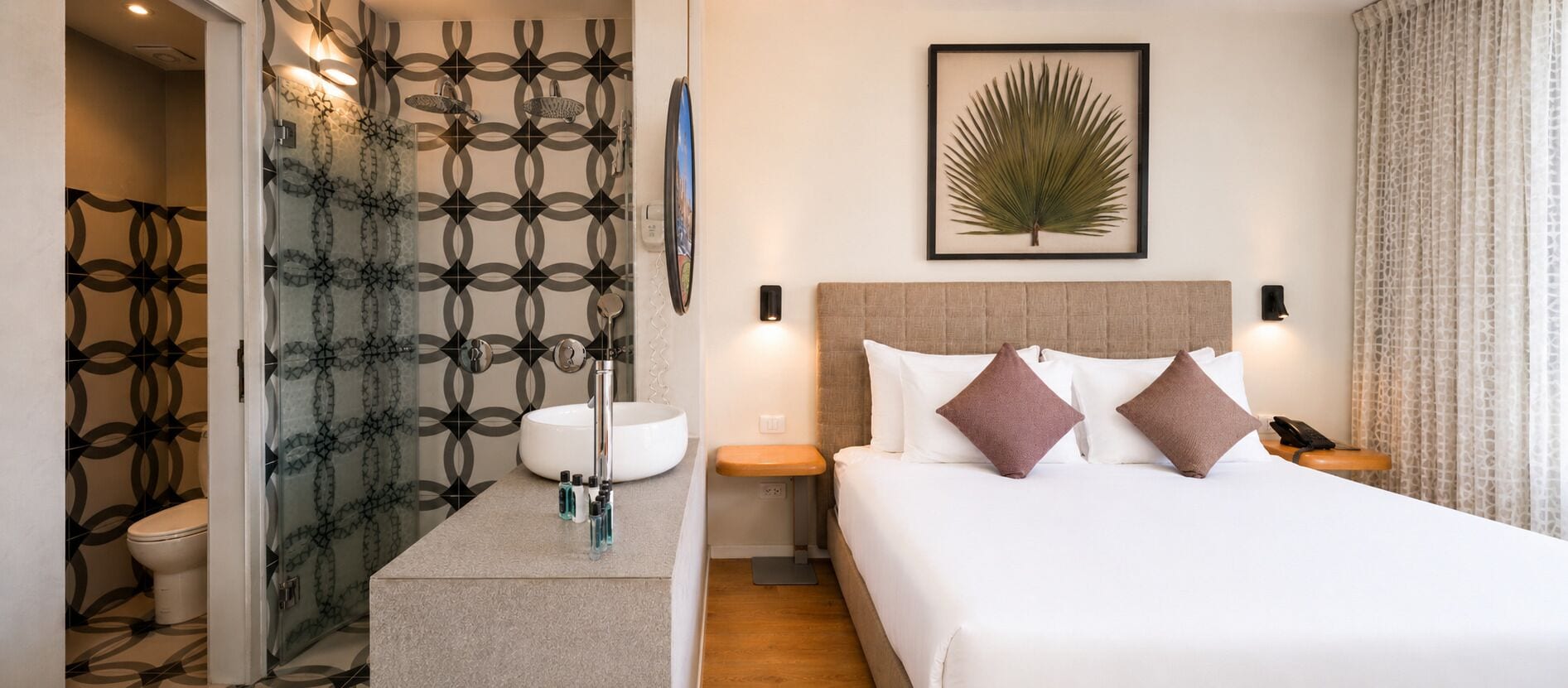 Habitación de hotel con cama, mesita de noche y baño con inodoro y lavabo.