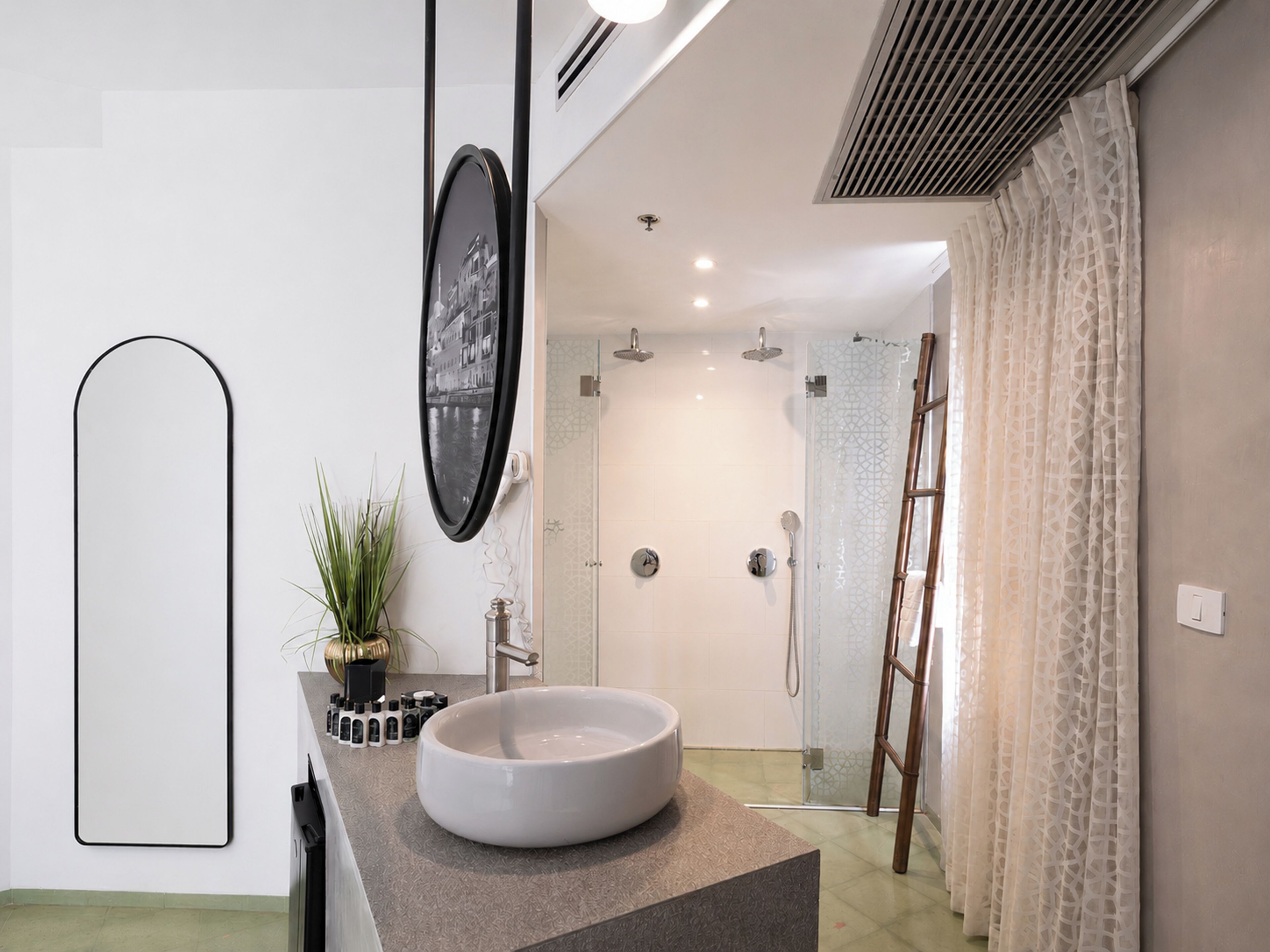 A modern bathroom with a large white sink, a mirror, and a shower area.