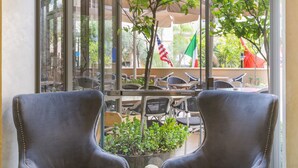 Una habitación con dos sillones, una mesita con un jarrón de rosas rojas y una botella.