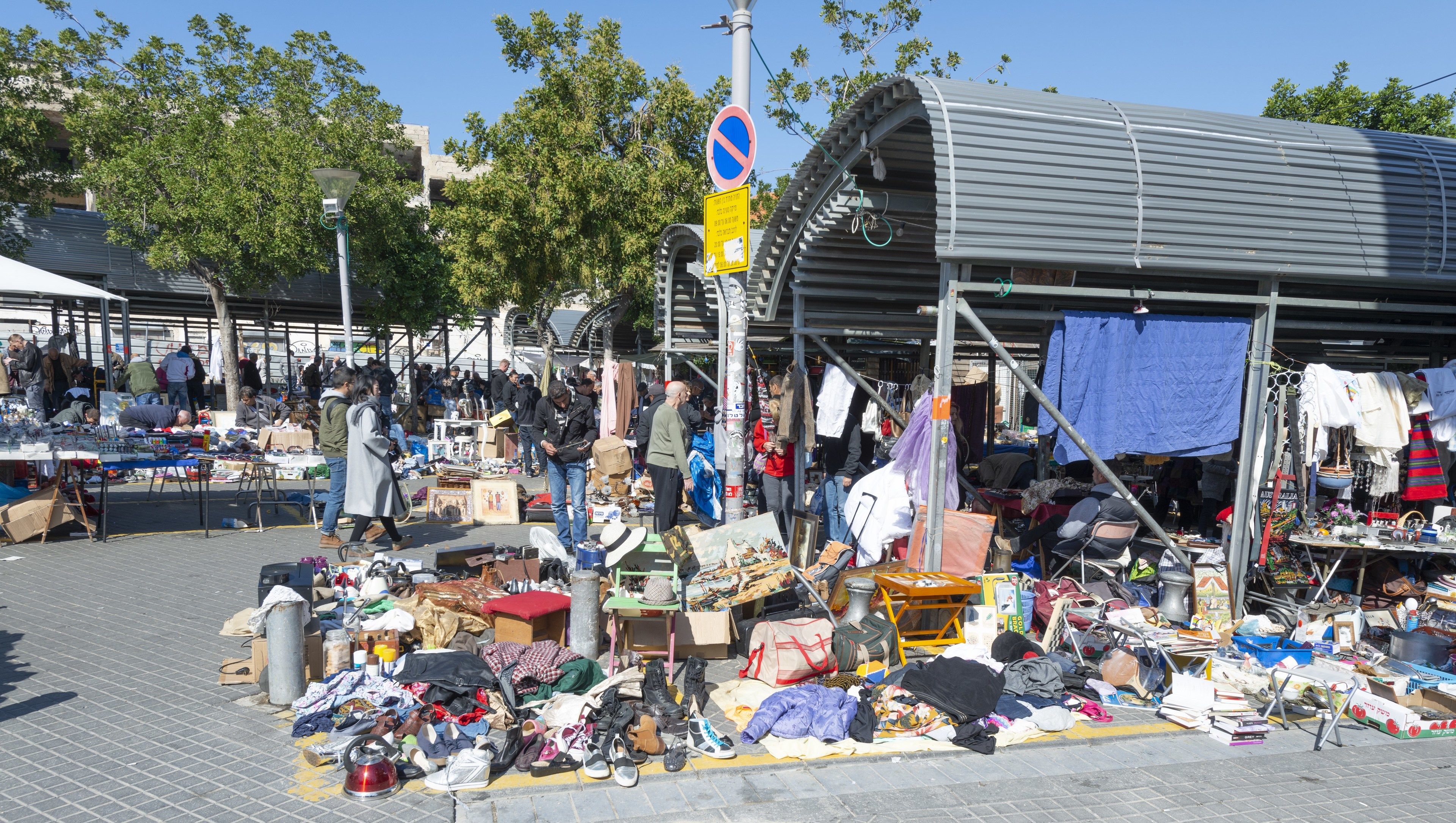 Un mercato all'aperto con numerosi banchi che vendono abiti e scarpe.