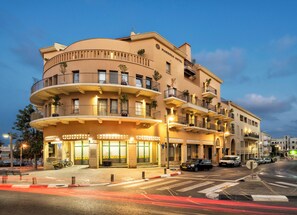 A multi-story hotel with balconies, a ground-level entrance, and a street view with cars and a pedestrian crossing. - Margosa Hotel (Tel Aviv)