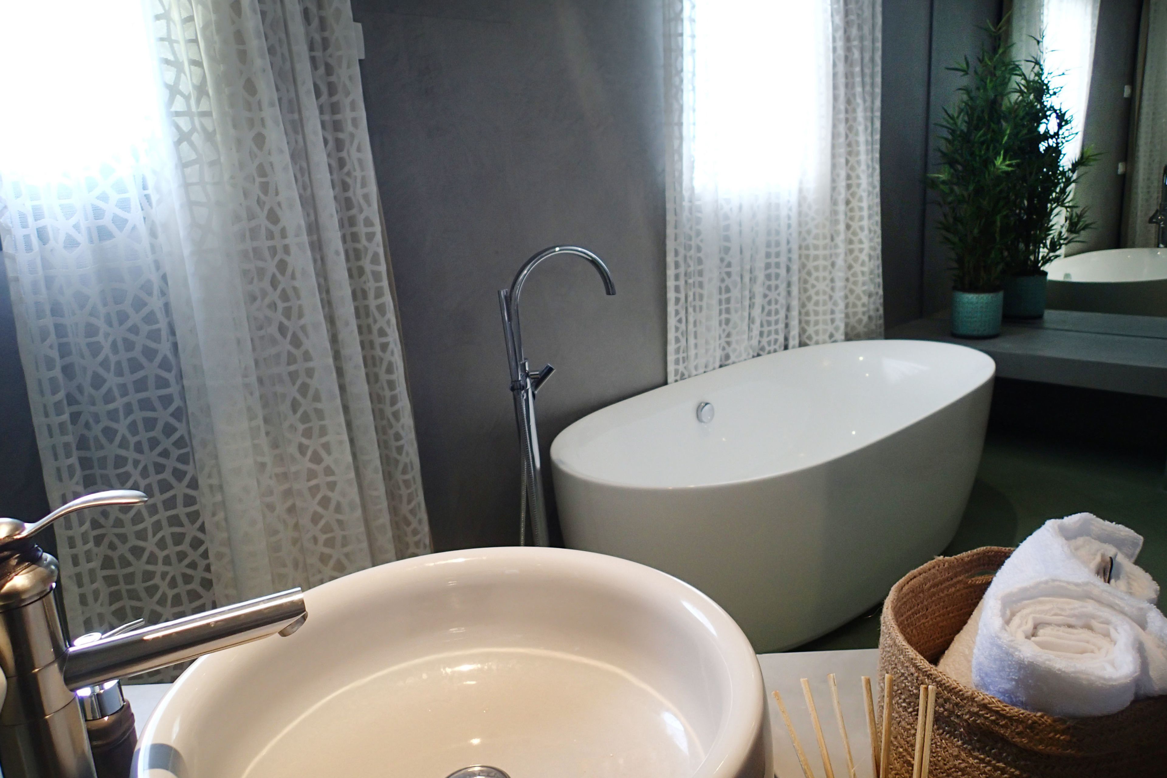 Un baño con lavamanos, bañera y cesta para toallas.