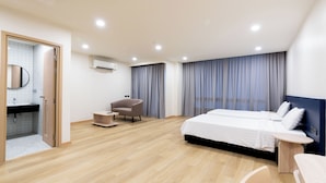 A modern hotel room with a large bed, a desk, a chair, and a bathroom with a mirror and sink. - CA Hotel and Residence Phuket (Ratsada)