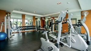 A gym with cardio machines, weightlifting equipment, and a mirrored wall. - CA Hotel and Residence Phuket (Ratsada)