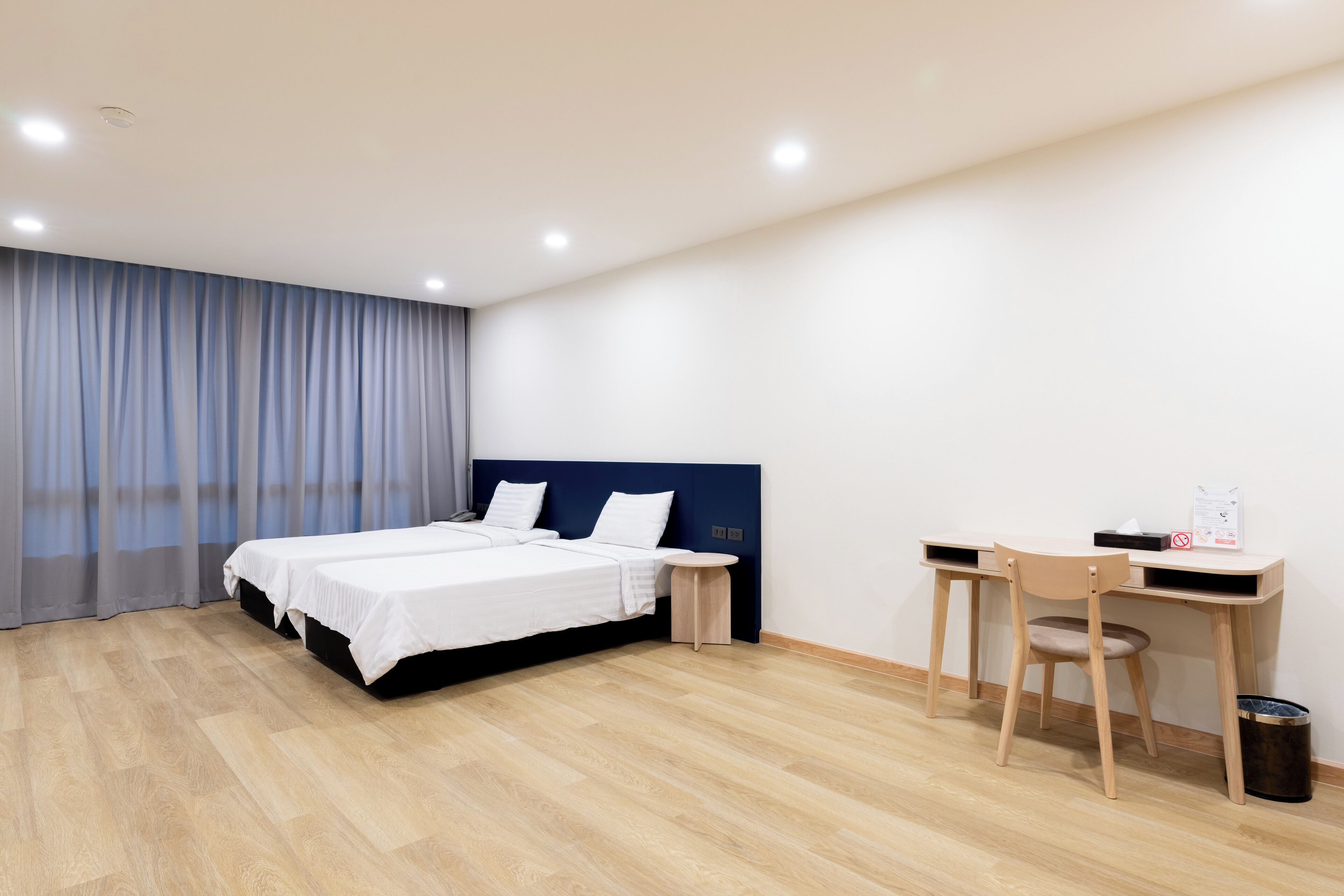 A modern hotel room with a bed, a desk, and a chair.