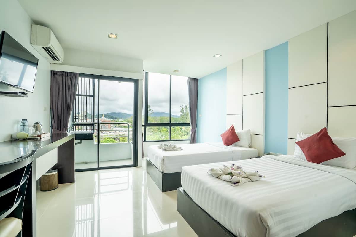 Une chambre d’hôtel avec deux lits, une télévision, un balcon avec vue et un bureau avec une chaise.