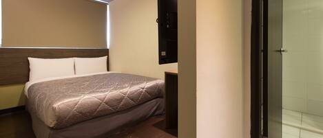 Una camera d'albergo con un letto, un comodino, uno specchio e una cabina doccia.