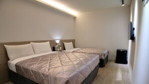 Habitación de hotel con dos camas, una mesita de noche, una lámpara y un altavoz negro.