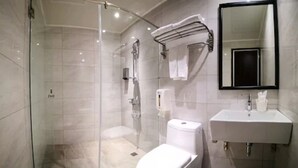 Un baño moderno con cabina de ducha de vidrio, un inodoro y un lavabo con espejo.