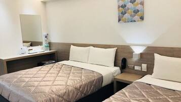 Une chambre d’hôtel avec deux lits, une table de chevet, un miroir et une œuvre d’art accrochée au mur.