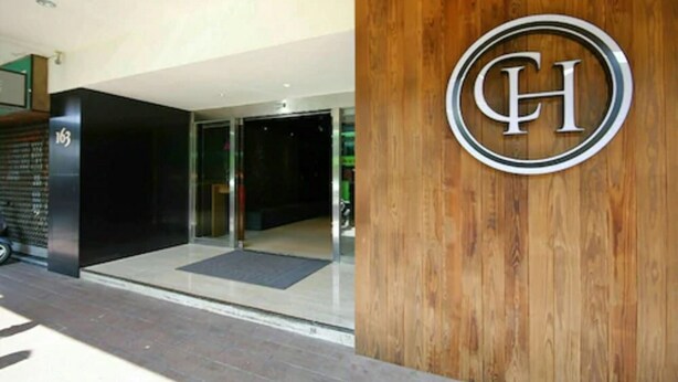 Entrada de hotel con fachada de madera y puerta de vidrio.