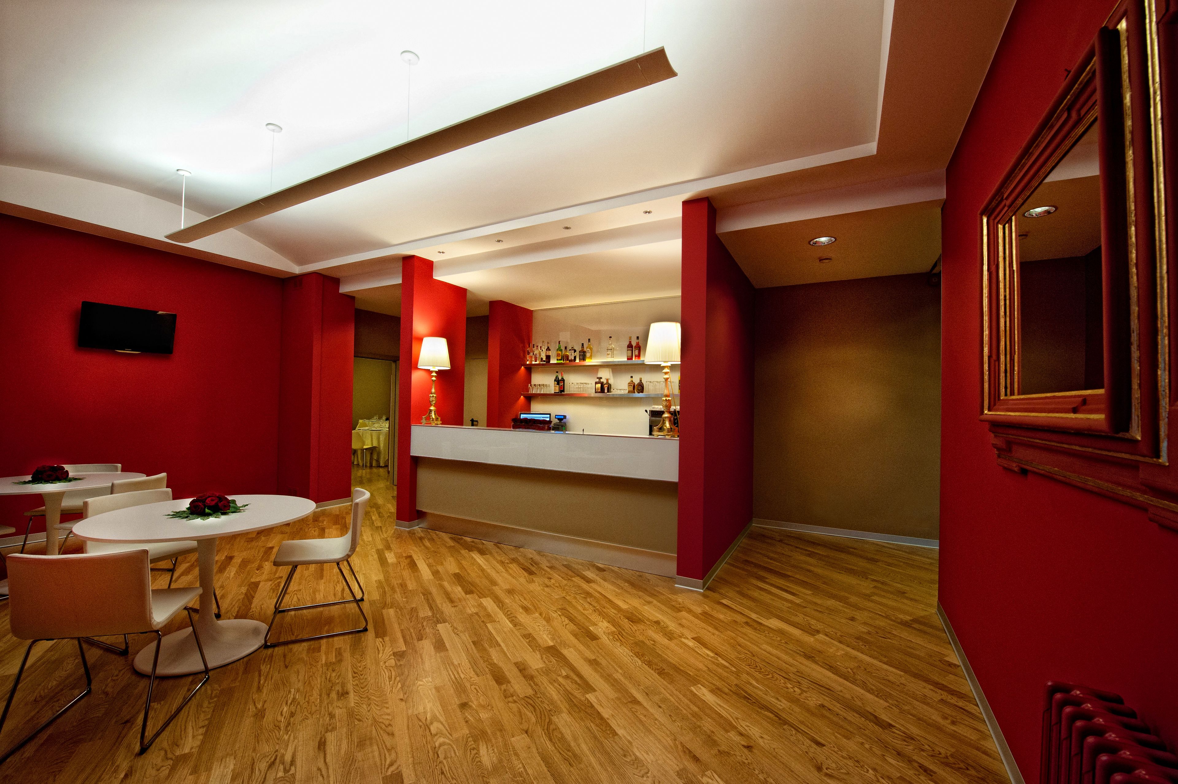 Un moderno vestíbulo de hotel con paredes rojas, suelo de madera y un mostrador de recepción.