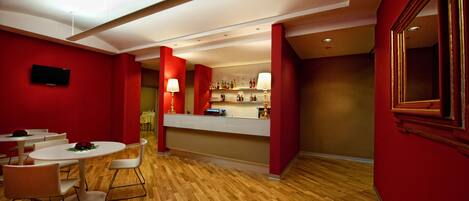 Un moderno vestíbulo de hotel con paredes rojas, suelo de madera y un mostrador de recepción.