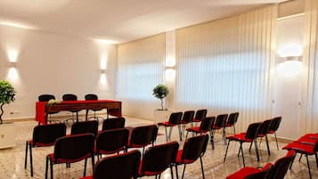 A conference room with a long table, multiple chairs, and a potted plant.