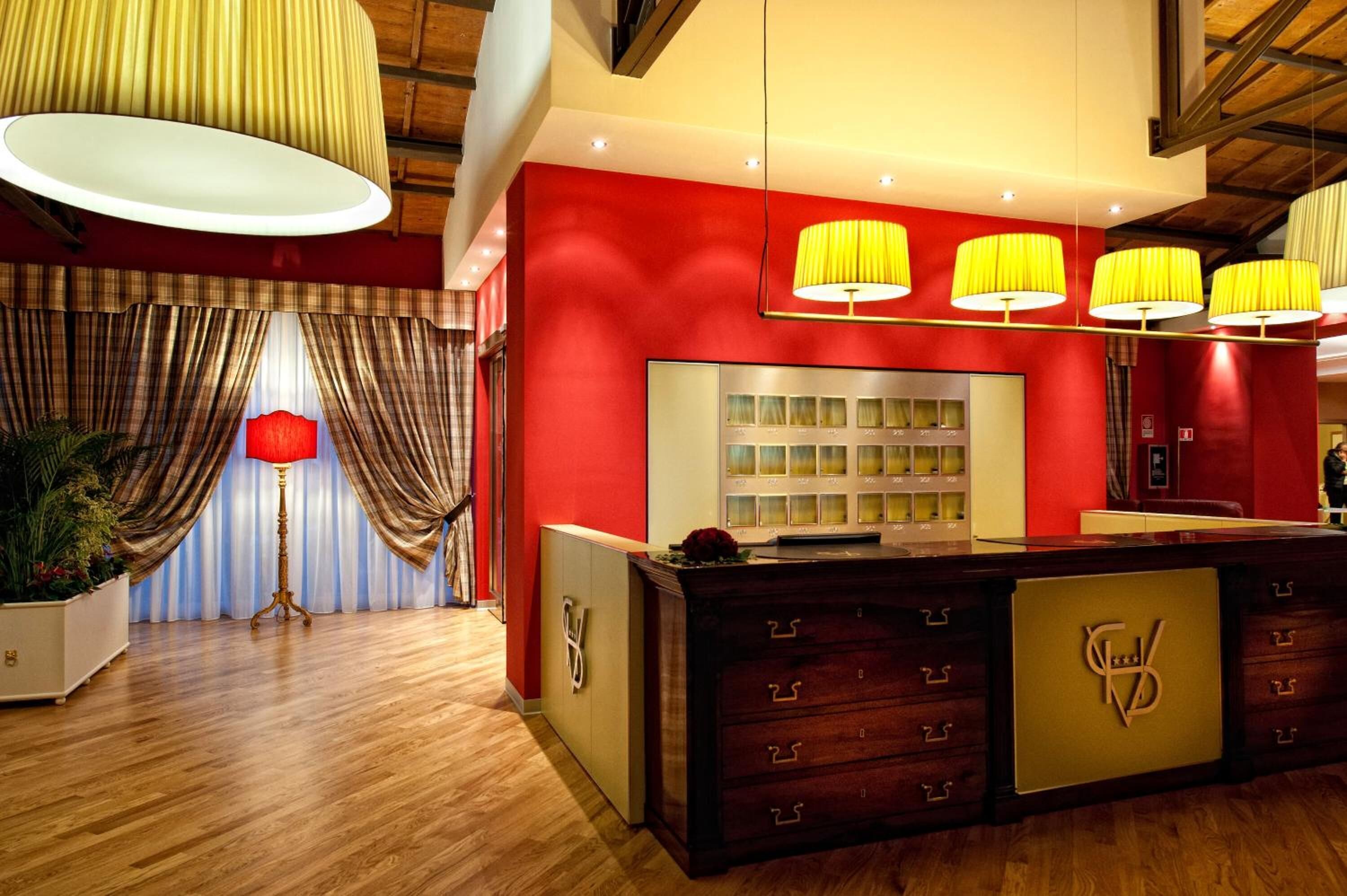 Et receptionområde med en rød væg, en træreception og en stor hængende lampe.