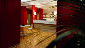 Una zona de bar moderna con suelo de madera, paredes rojas y una barra blanca.
