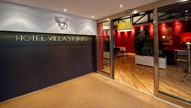 Una entrada de hotel moderna con un cartel que dice "HOTEL VILLA STURZO".