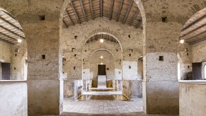 Un interior amb sostres arquejats, parets de pedra i un passatge central que condueix a una porta.