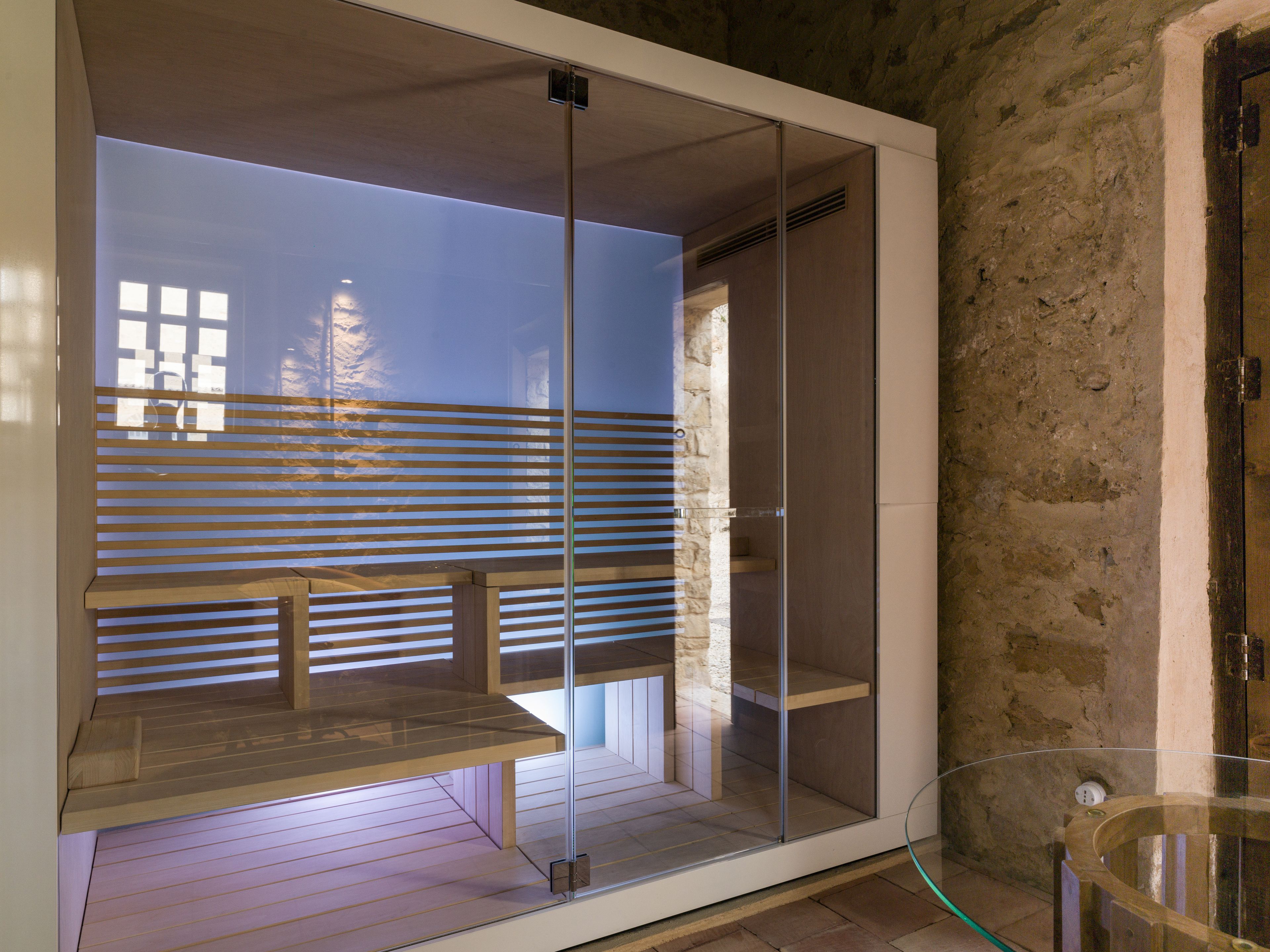 Ein modernes Zimmer mit Glastrennwand, einer Holzbank und einer Steinwand.