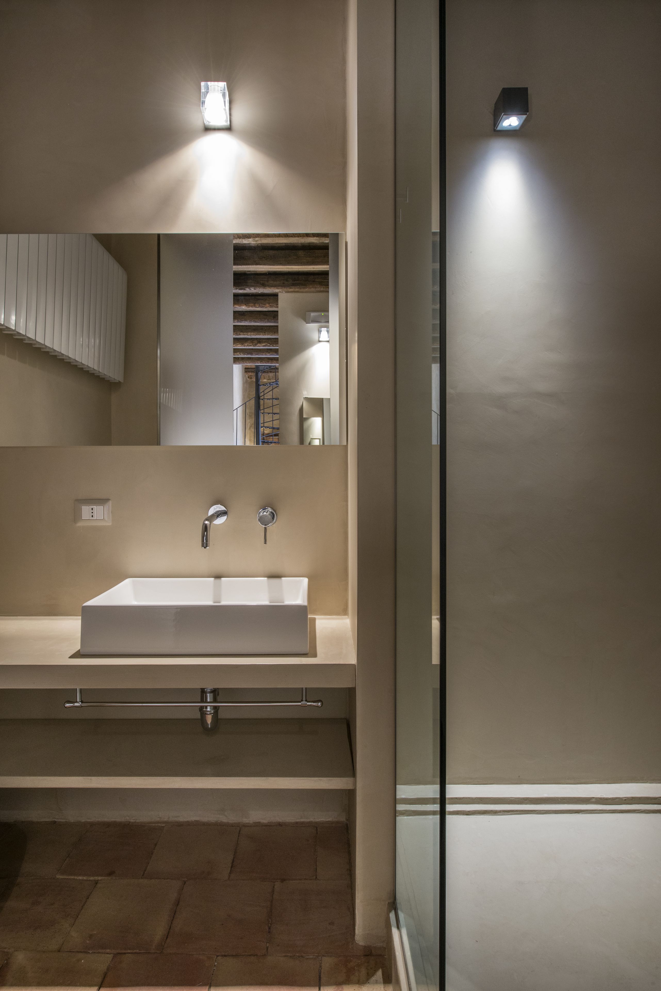 A modern bathroom with a large mirror, a rectangular sink, and a glass shower enclosure.