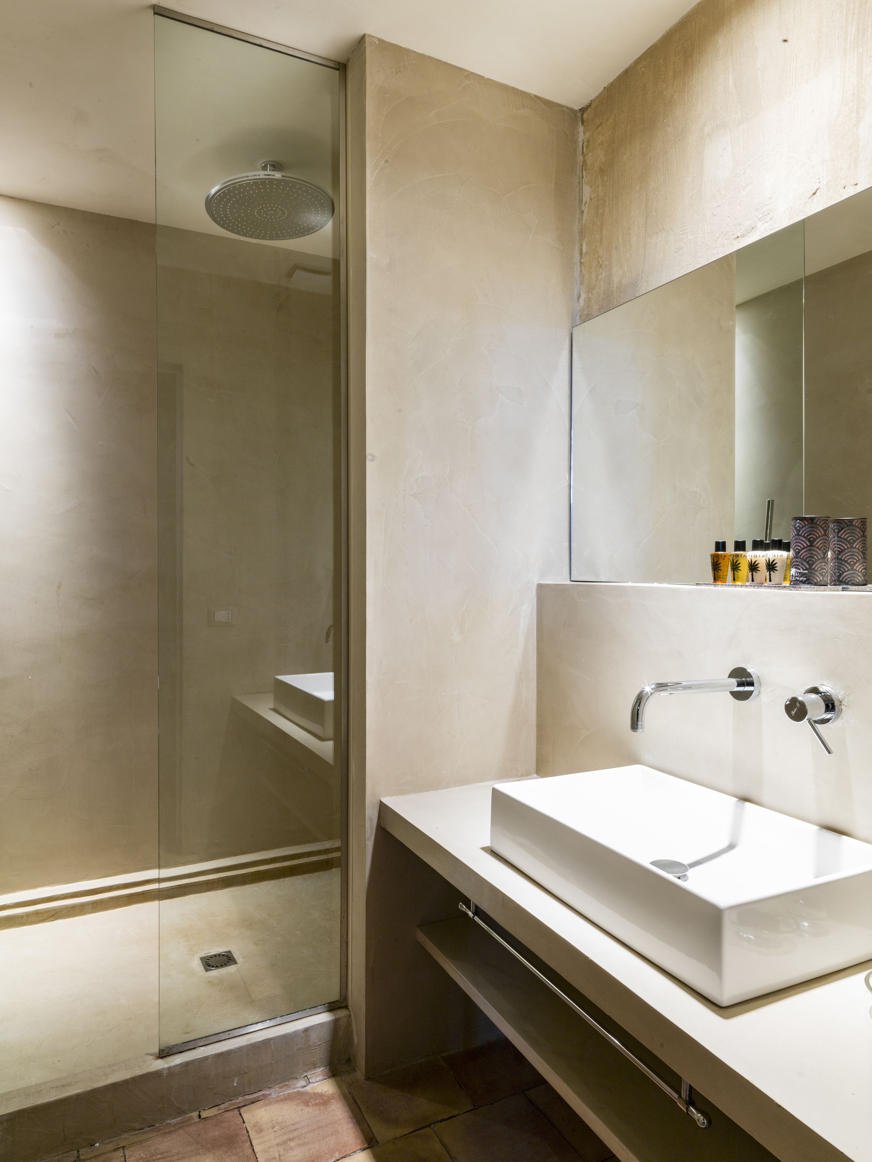 A modern bathroom with a glass-enclosed shower, a white sink, and a large mirror.