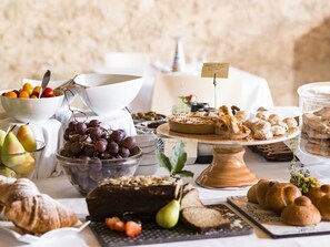 A buffet table with various food items including a cake, pastries, fruits, and bread. - Wine Relais Feudi del Pisciotto (Niscemi)