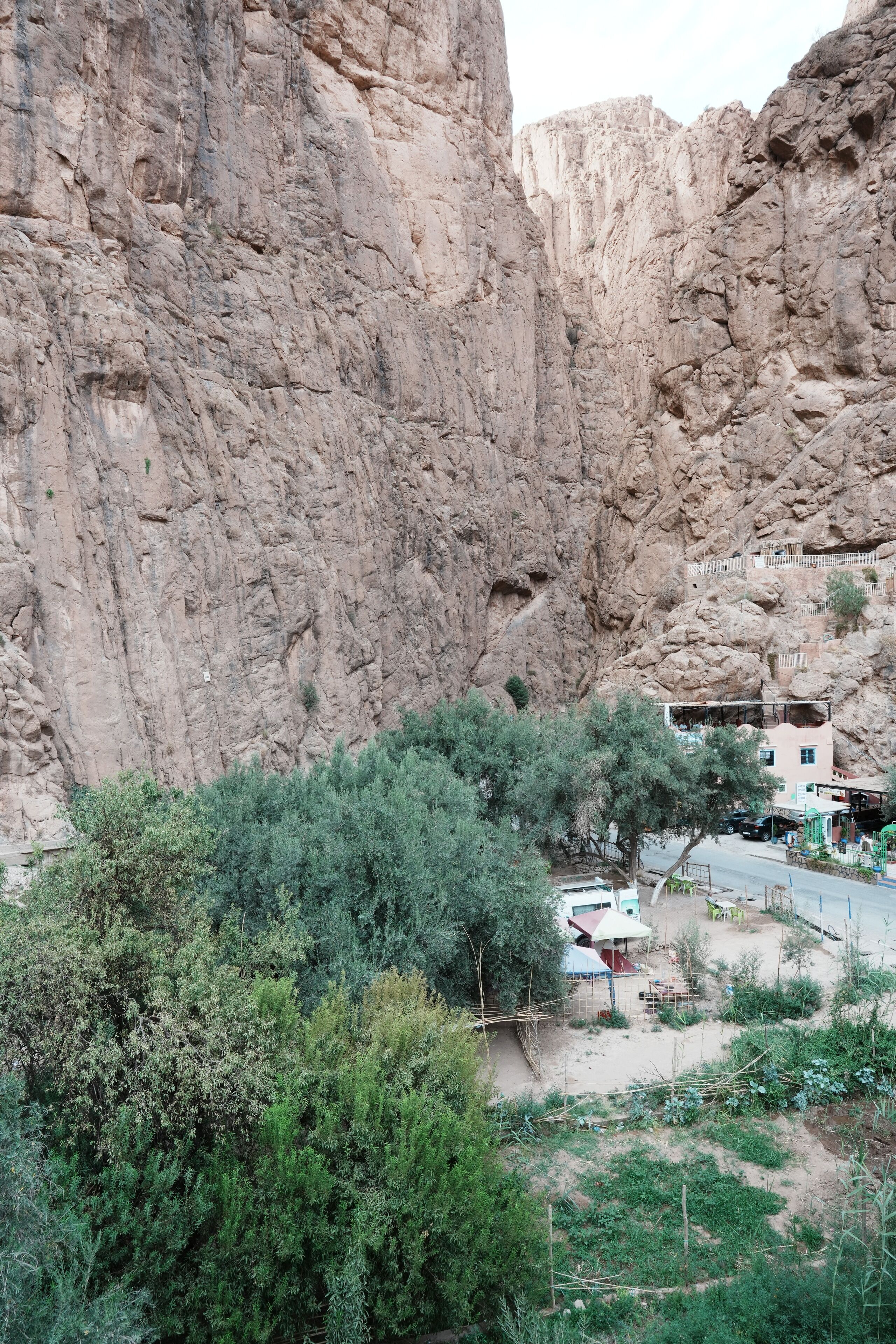 A rocky cliff with a small building and greenery in the foreground.
