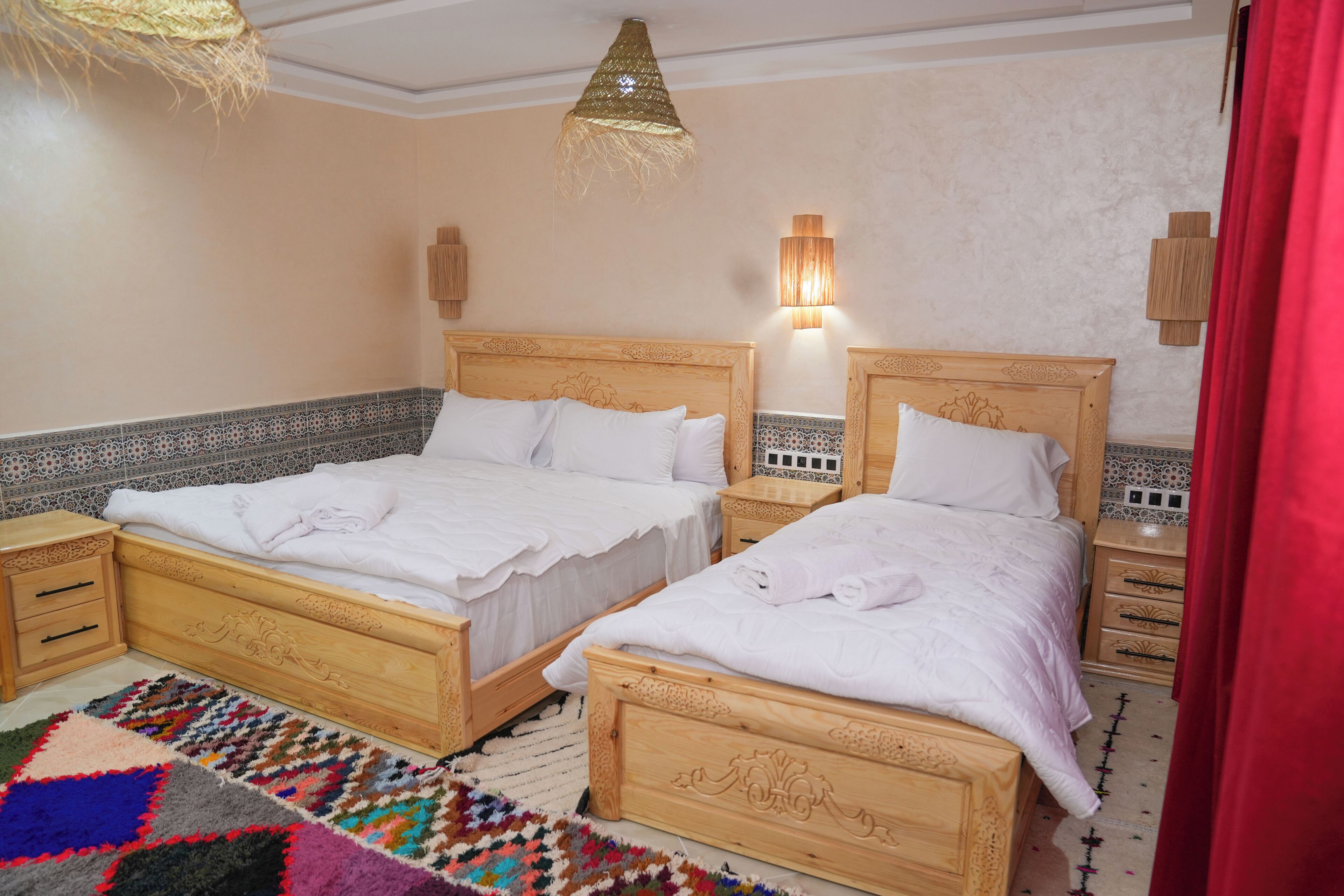 Una cama doble con cabecera de madera, una mesita de noche y una alfombra estampada.