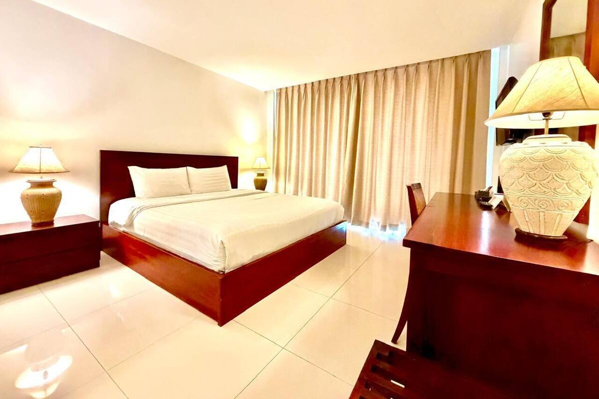 A hotel room with a bed, a desk, a lamp, and a chair.