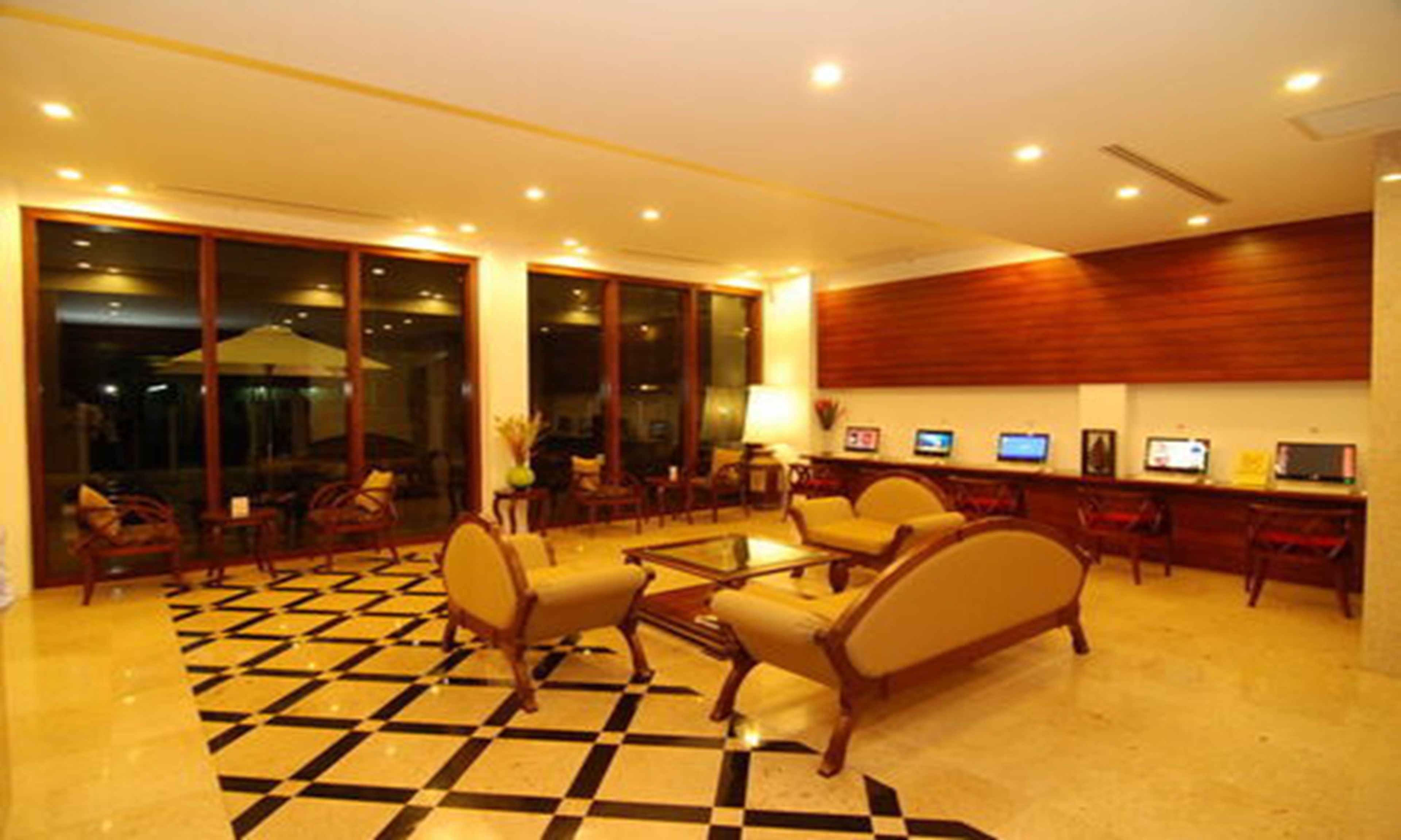 A hotel lobby with a checkered floor, seating area, and a reception desk with computers.