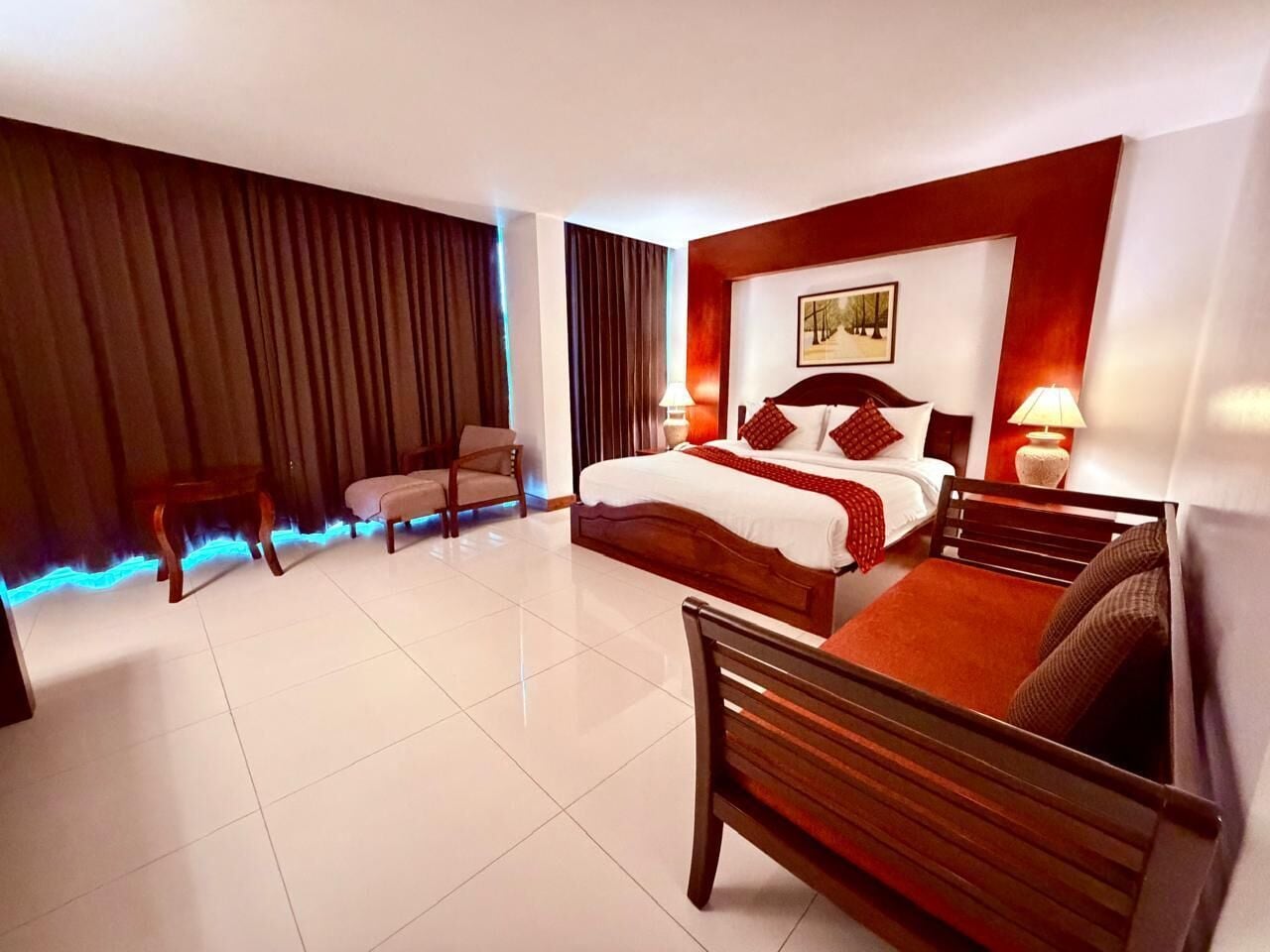 Ein Hotelzimmer mit Bett, Sessel, Schreibtisch und Lampe.