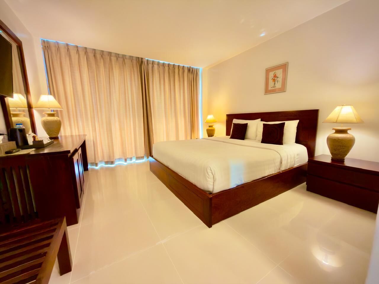 Habitación de hotel con una cama grande, mesitas de noche, un escritorio y un espejo.