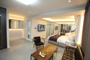 A hotel room with a bed, a desk, a chair, a television, and a bathroom with a mirror. - 500th Hotel (Mokpo)