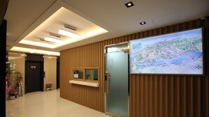 A hotel reception area with a modern design, a reception desk, a large map display, and a wooden panel wall. - 500th Hotel (Mokpo)