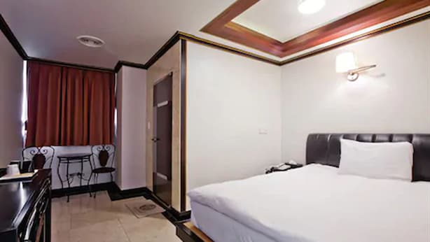 Une chambre d’hôtel avec un lit, un bureau, une chaise et une petite table.