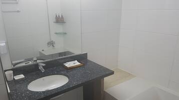 Un baño con lavamanos blanco, espejo, ducha y bañera.