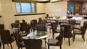 Un espace repas avec des tables et des chaises rondes, un buffet et un mur orné de panneaux d’information.