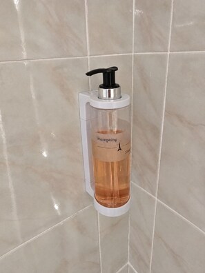 Baño con dispensador de jabón líquido en una pared de azulejos.