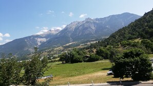 A mountainous landscape with a clear sky, a road with a parked car, and a sign indicating a leisure area.