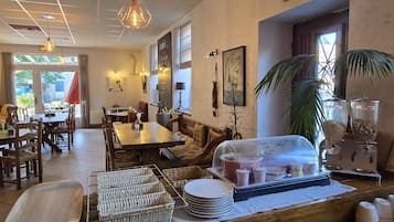 A restaurant interior with a dining area, a counter with food service items, and a view of the outdoors.