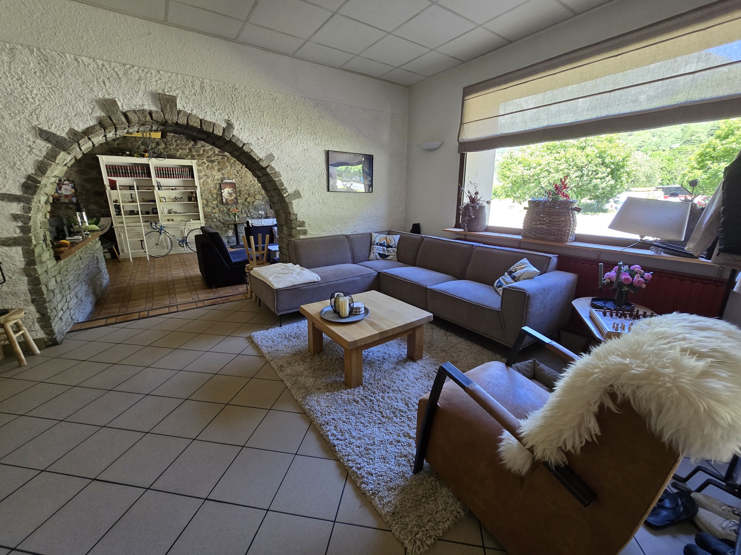 Ein gemütliches Wohnzimmer mit einem Steingewölbe, einer Couch, einem Couchtisch und Blick ins Grüne.