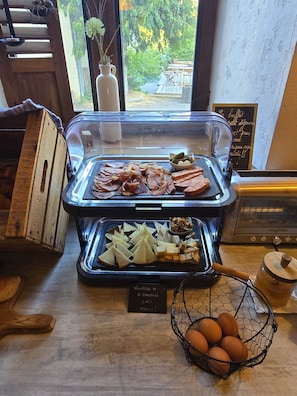 Un bufé de desayuno con diferentes carnes, quesos y huevos.