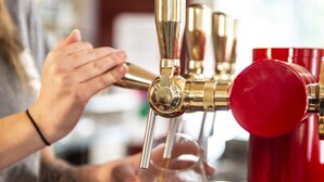 A person pouring beer from a tap into a glass.