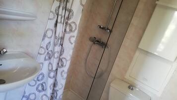 A bathroom with a shower, toilet, and sink.
