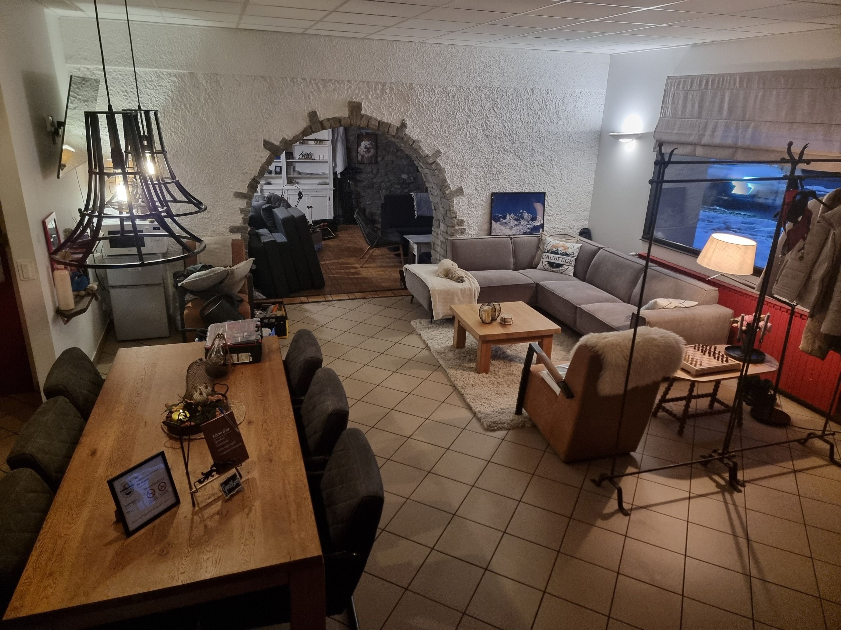 Un espacio de sala acogedor con un arco de piedra, una mesa de comedor de madera y un sofá cómodo.
