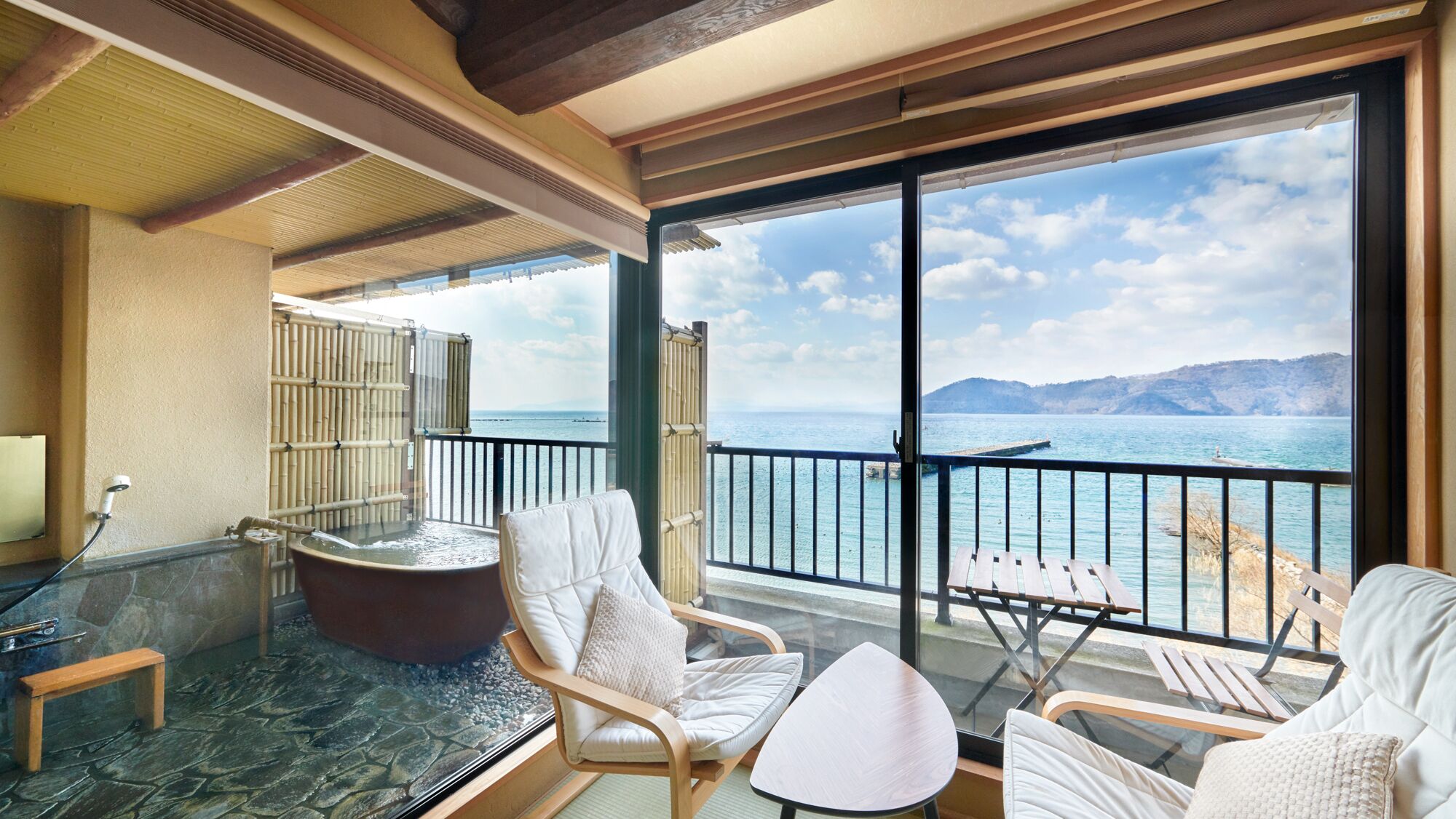 A balcony with a hot tub, seating area, and a view of the sea.